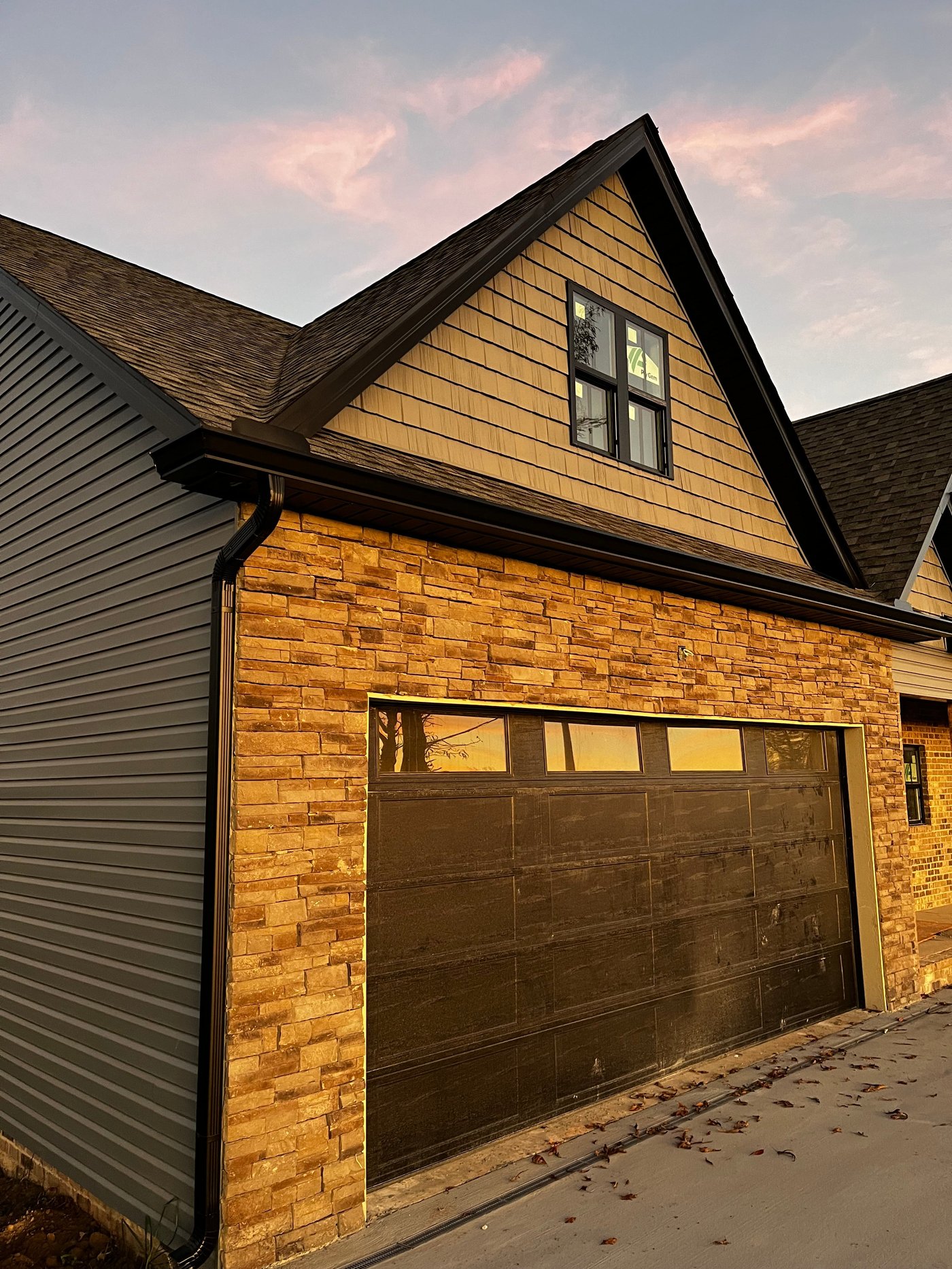 Gutter and downspout on a stone-and-shingle exterior by Gutter And Covers, Cookeville