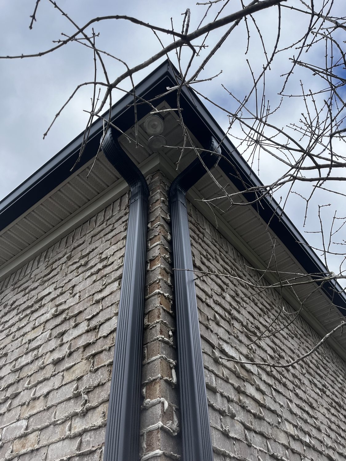 Downspout and gutter corner on a brick home by Gutter And Covers, Cookeville