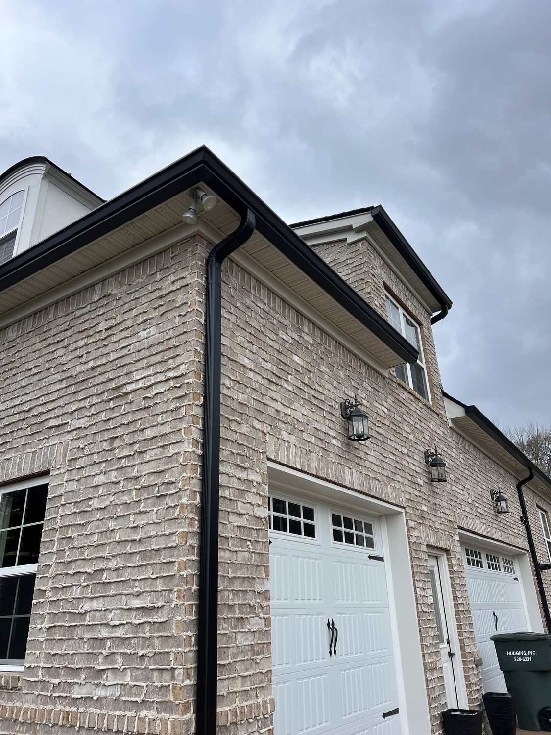 Full gutter and downspout on a two-story brick home by Gutter And Covers, Cookeville