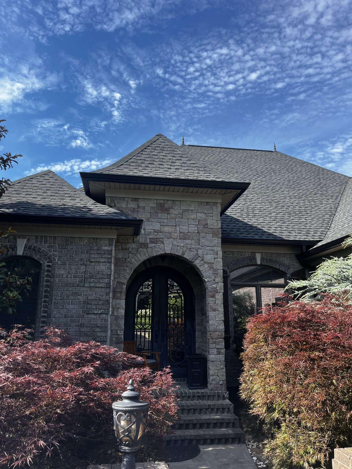 Seamless gutters on a stone home with an arched entry by Gutter And Covers, Cookeville