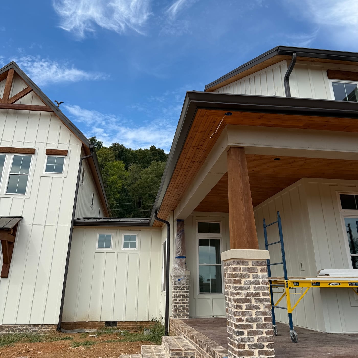 Dark gutters and downspouts on a white farmhouse porch by Gutter And Covers, Cookeville