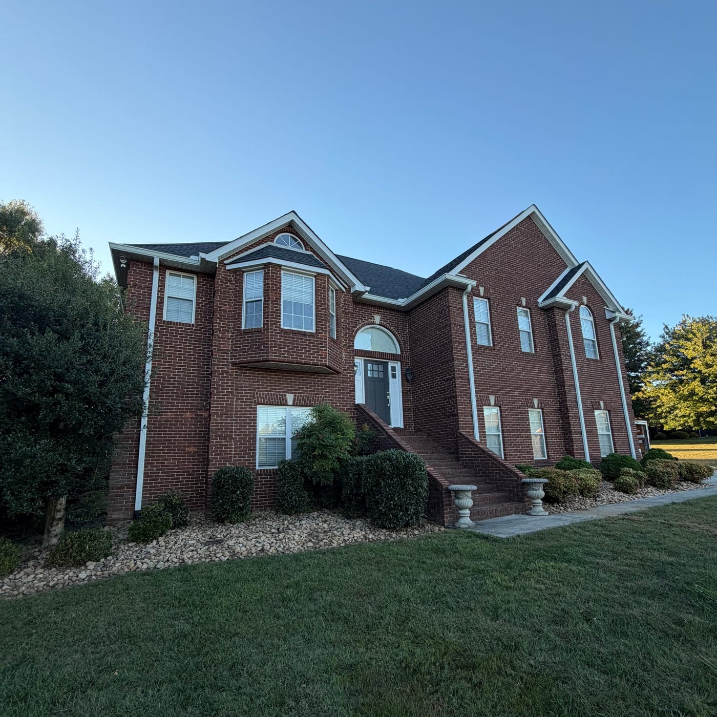 White gutters and downspouts on a two-story brick home by Gutter And Covers, Cookeville